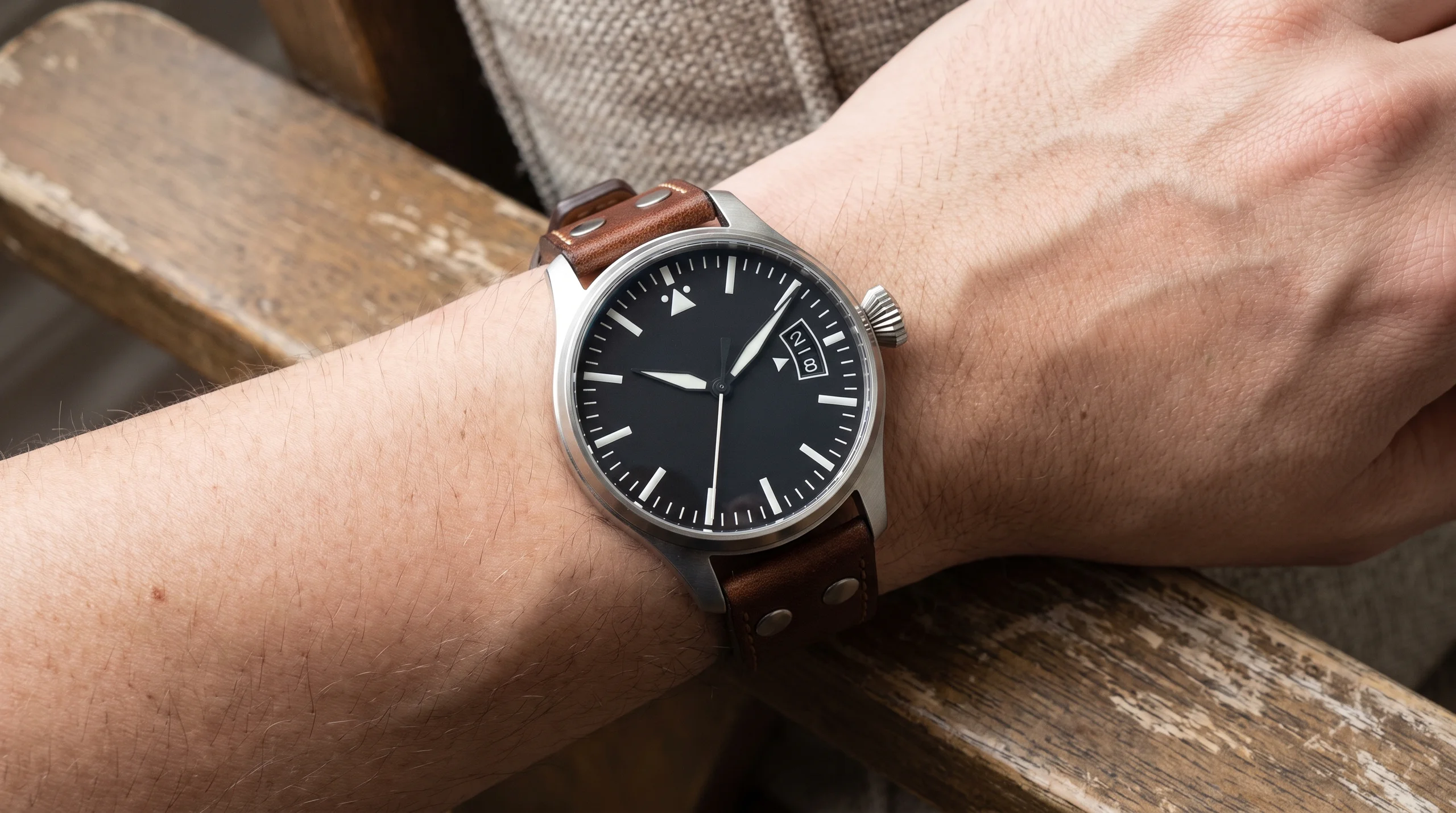 Large stainless steel pilot's watch with a wide big date window worn on the wrist, front angle