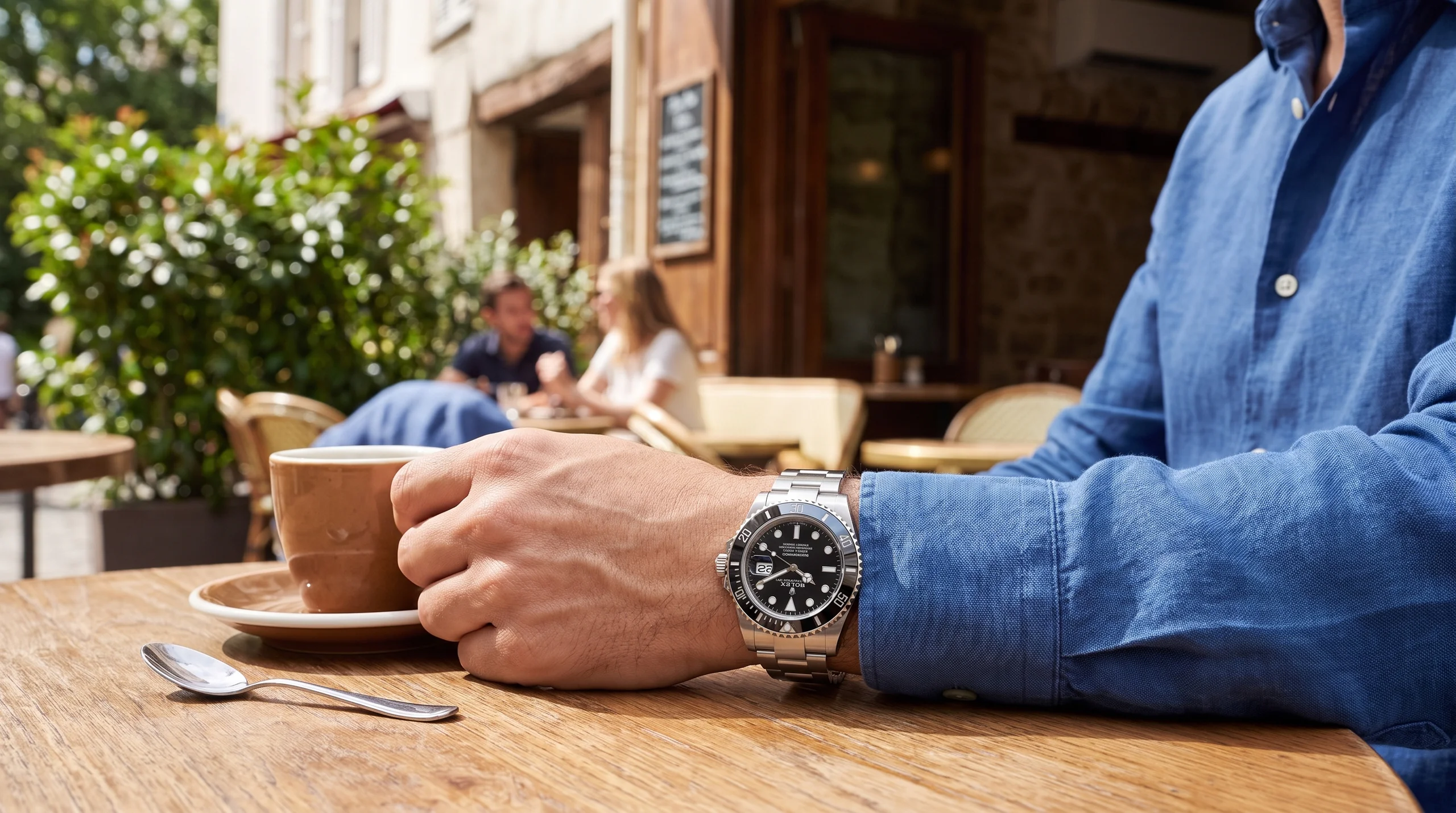 Person wearing a Rolex Submariner confidently at an outdoor cafe table