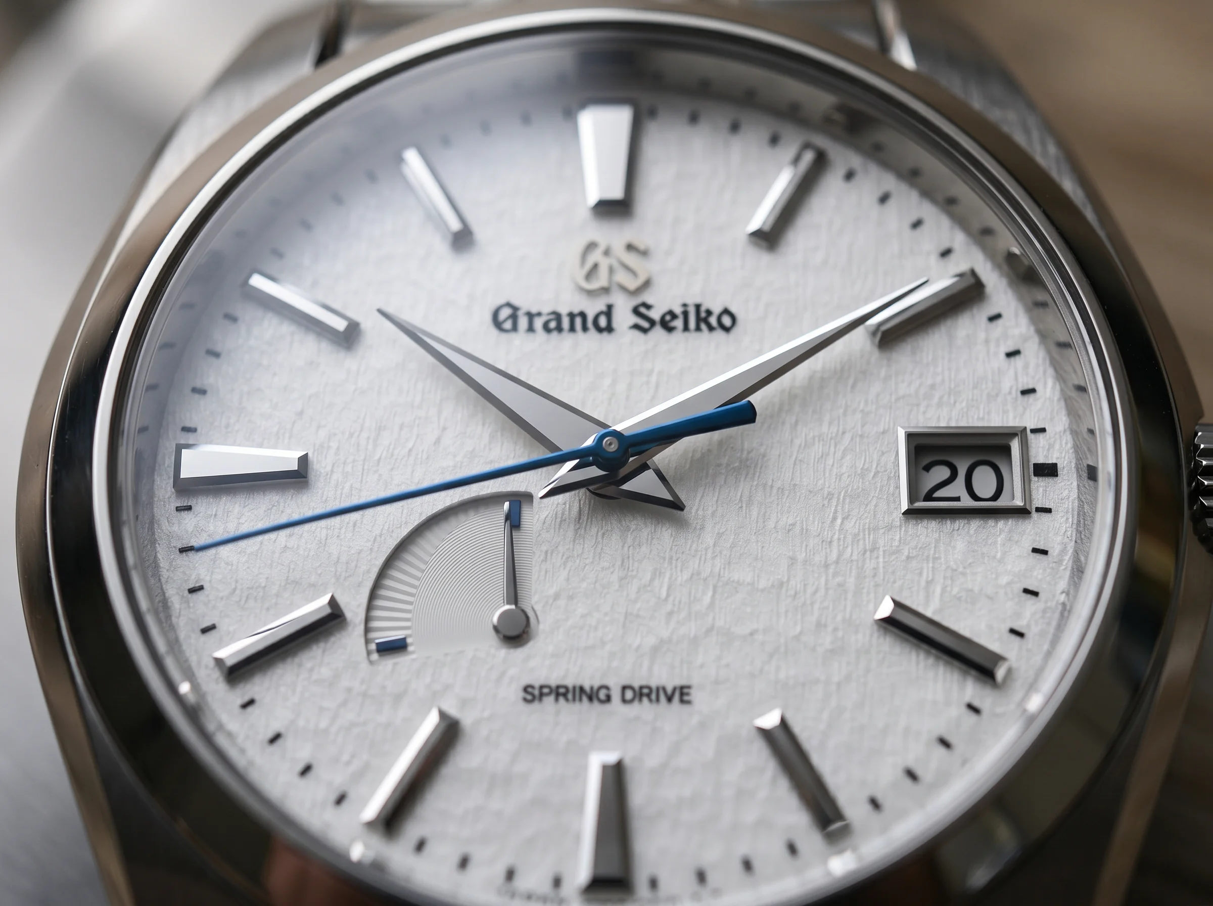 The blue gliding seconds hand of a Grand Seiko Spring Drive sweeping across its snow-textured silver dial