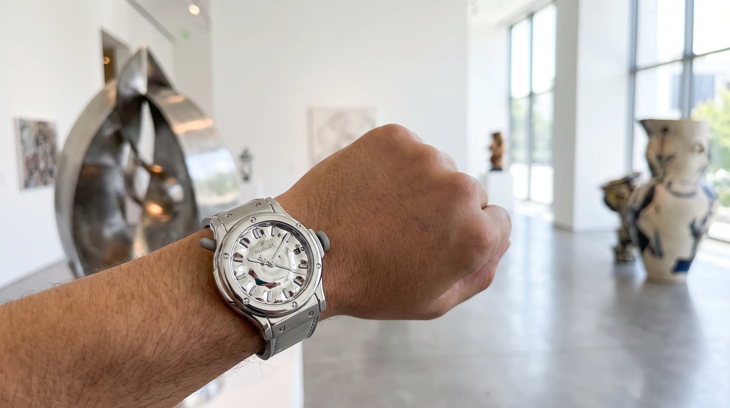 Collector wearing the silver Hublot Classic Fusion Balloon Dog watch in a contemporary art gallery