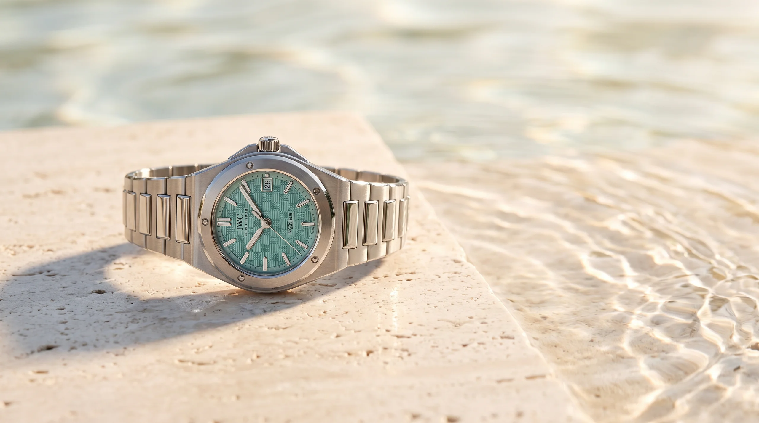IWC Ingenieur Automatic 35 Pool with turquoise grid dial on sunlit travertine beside water