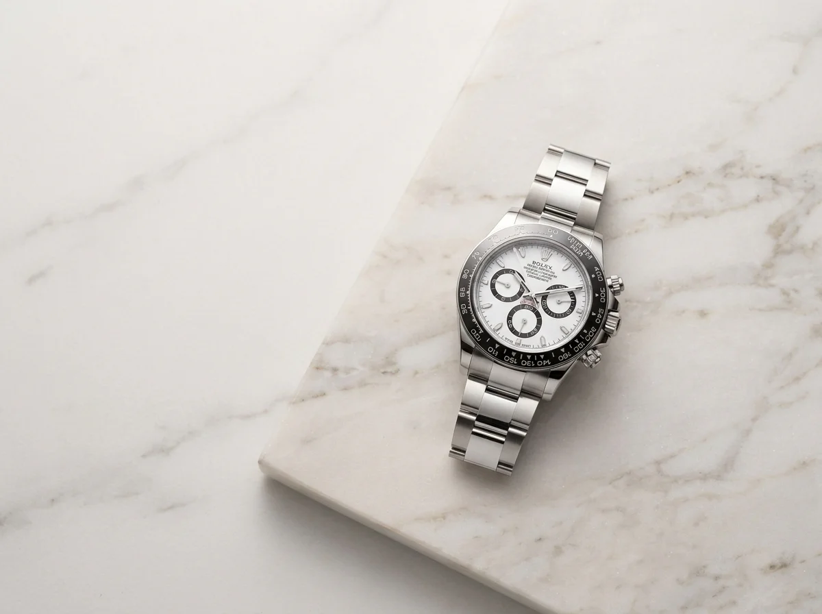 Steel white-dial Rolex Daytona on a pale marble slab.