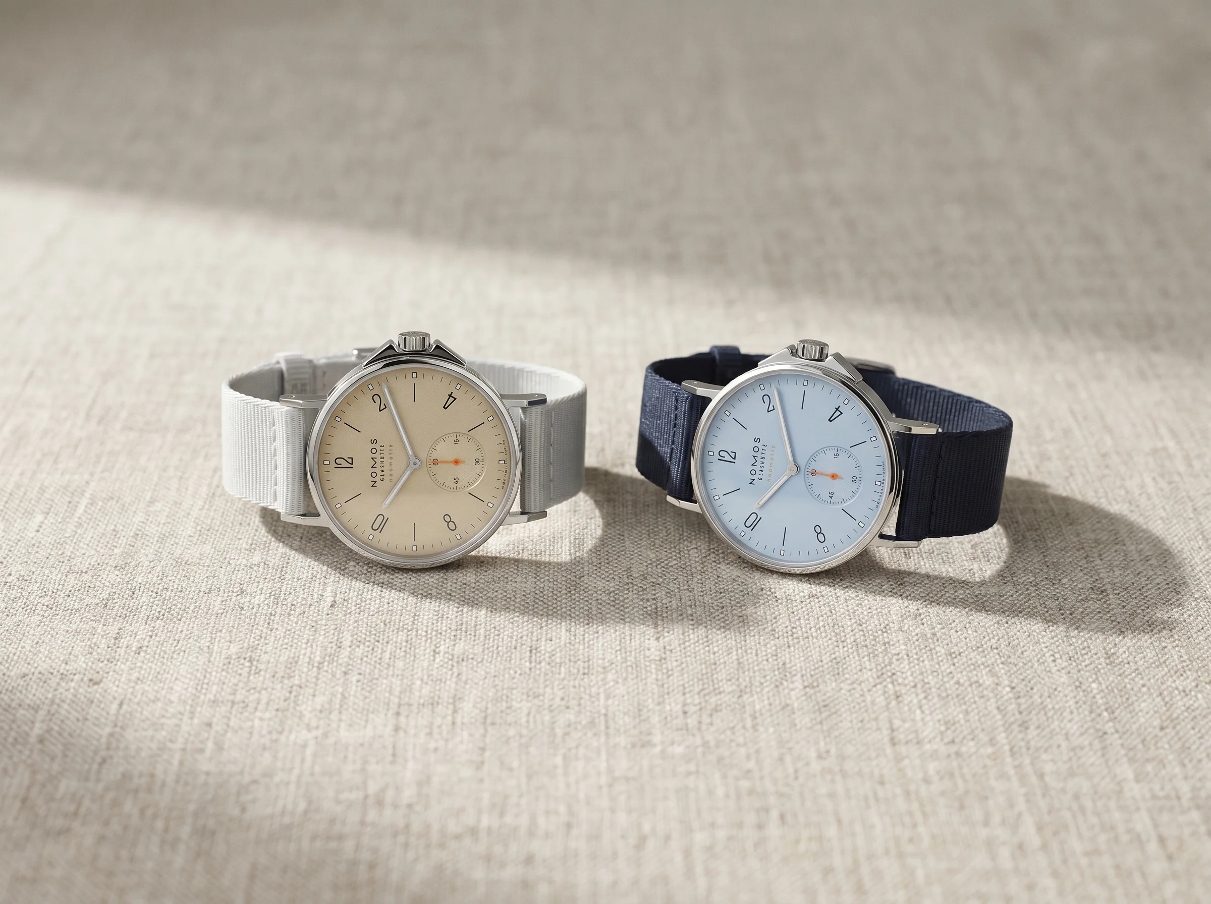 Nomos Ahoi Neomatik Sand and Sky side by side on linen, one beige dial and one pale blue dial