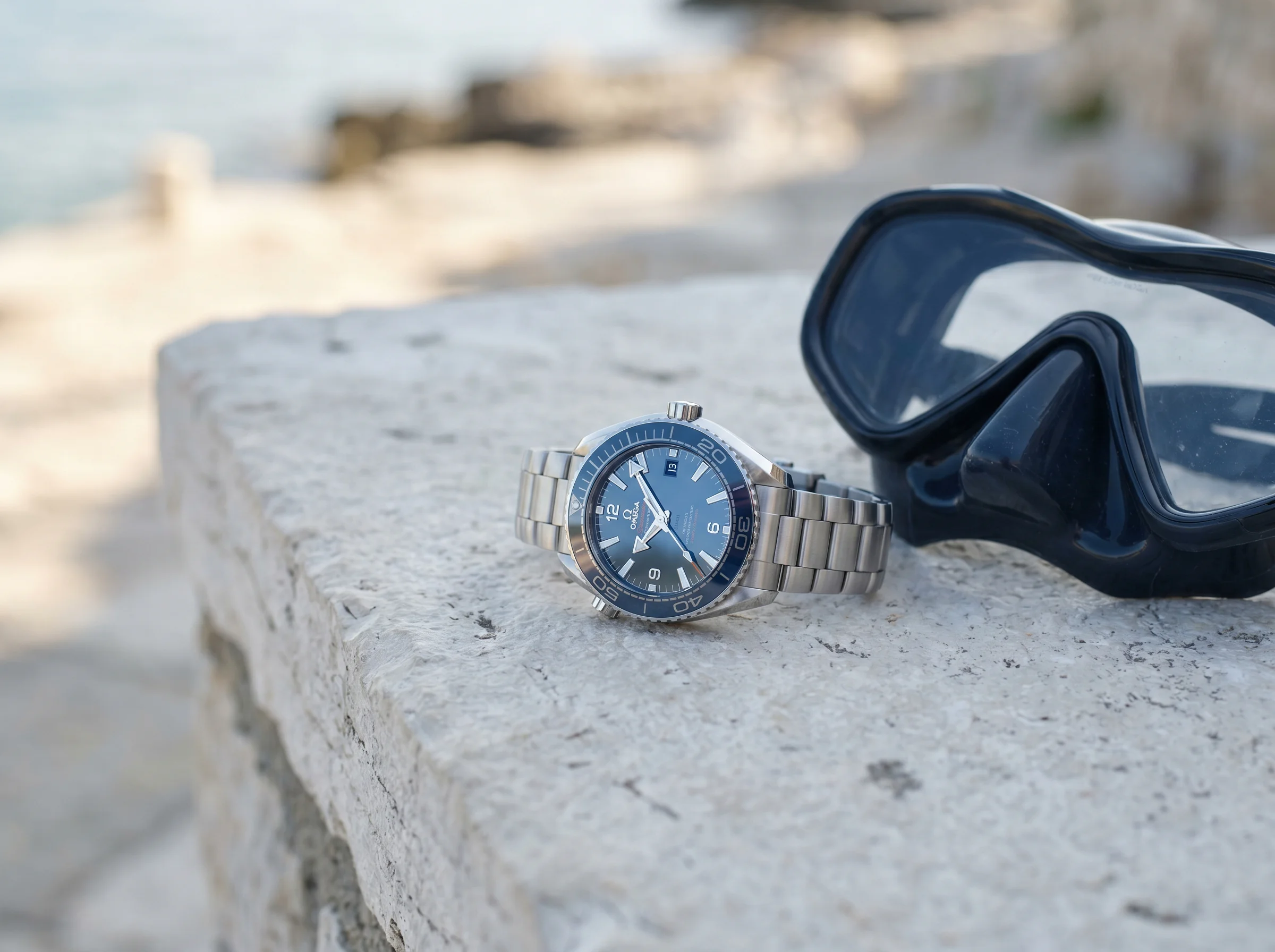 Omega Seamaster Planet Ocean 600M 39.5mm with blue ceramic dial and bezel beside a dive mask