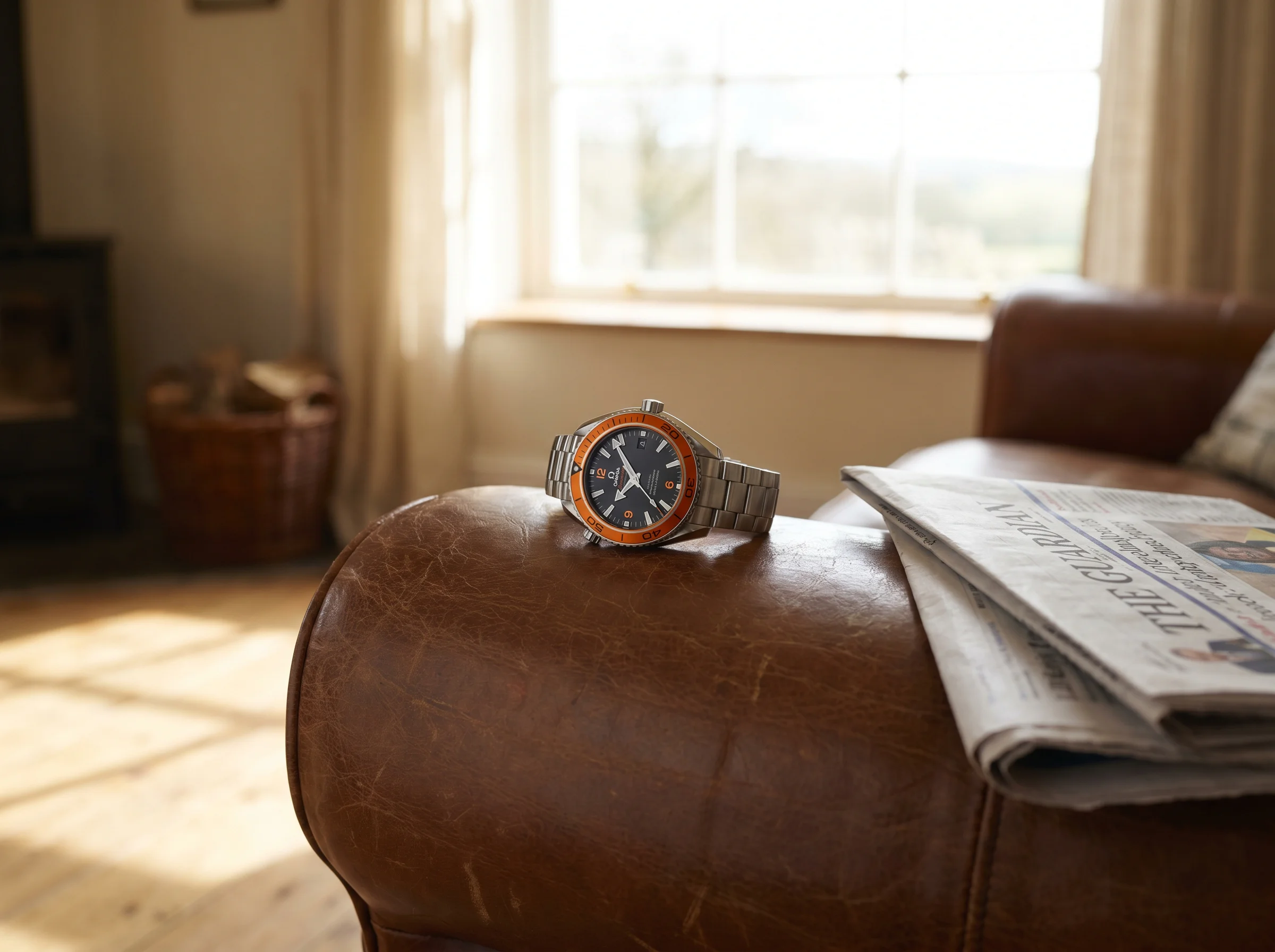 Omega Seamaster Planet Ocean 600M with signature orange ceramic bezel and black dial on a leather chair arm