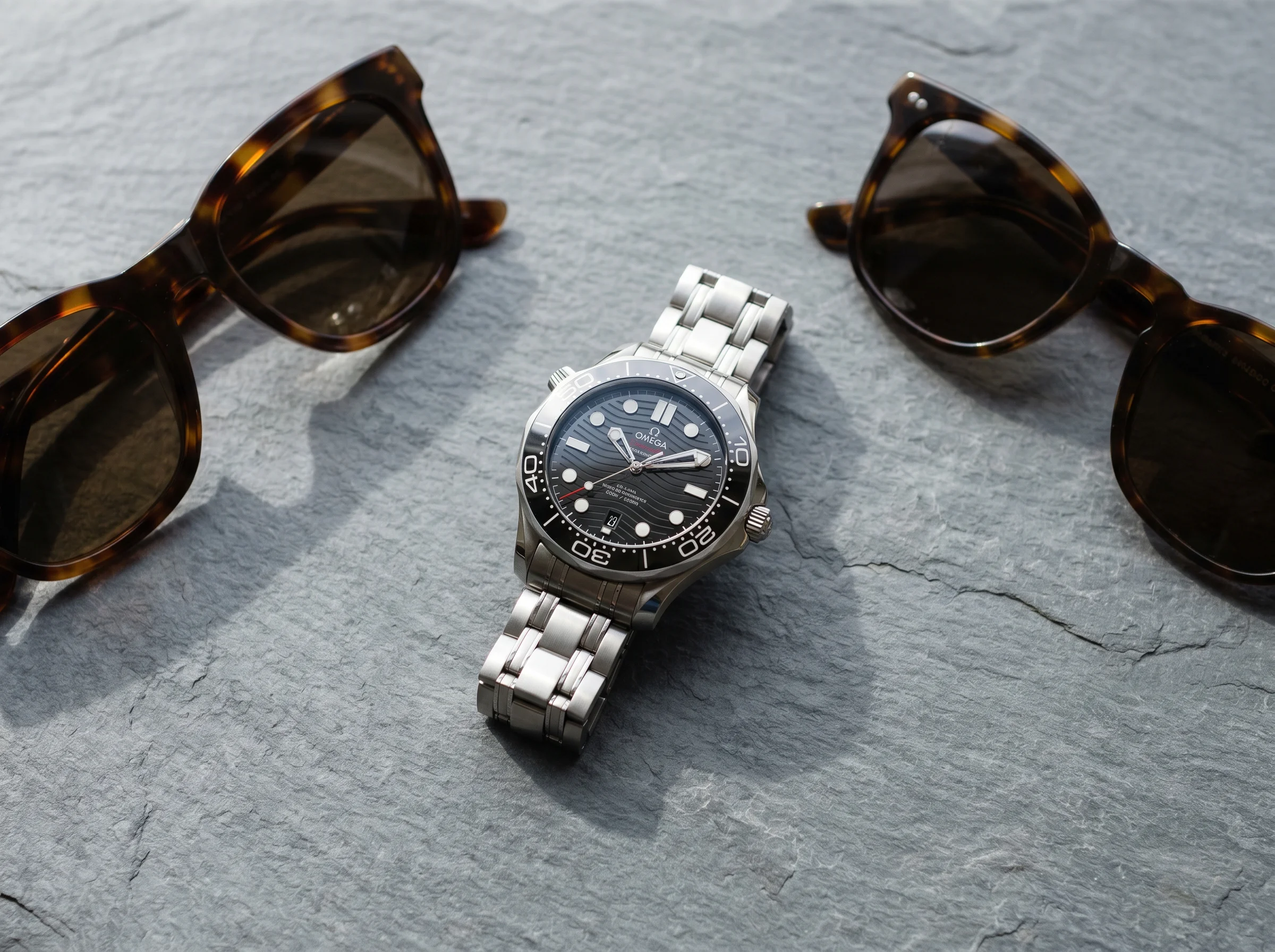 Omega Seamaster Diver 300M with black wave dial and date at six on a grey slate surface