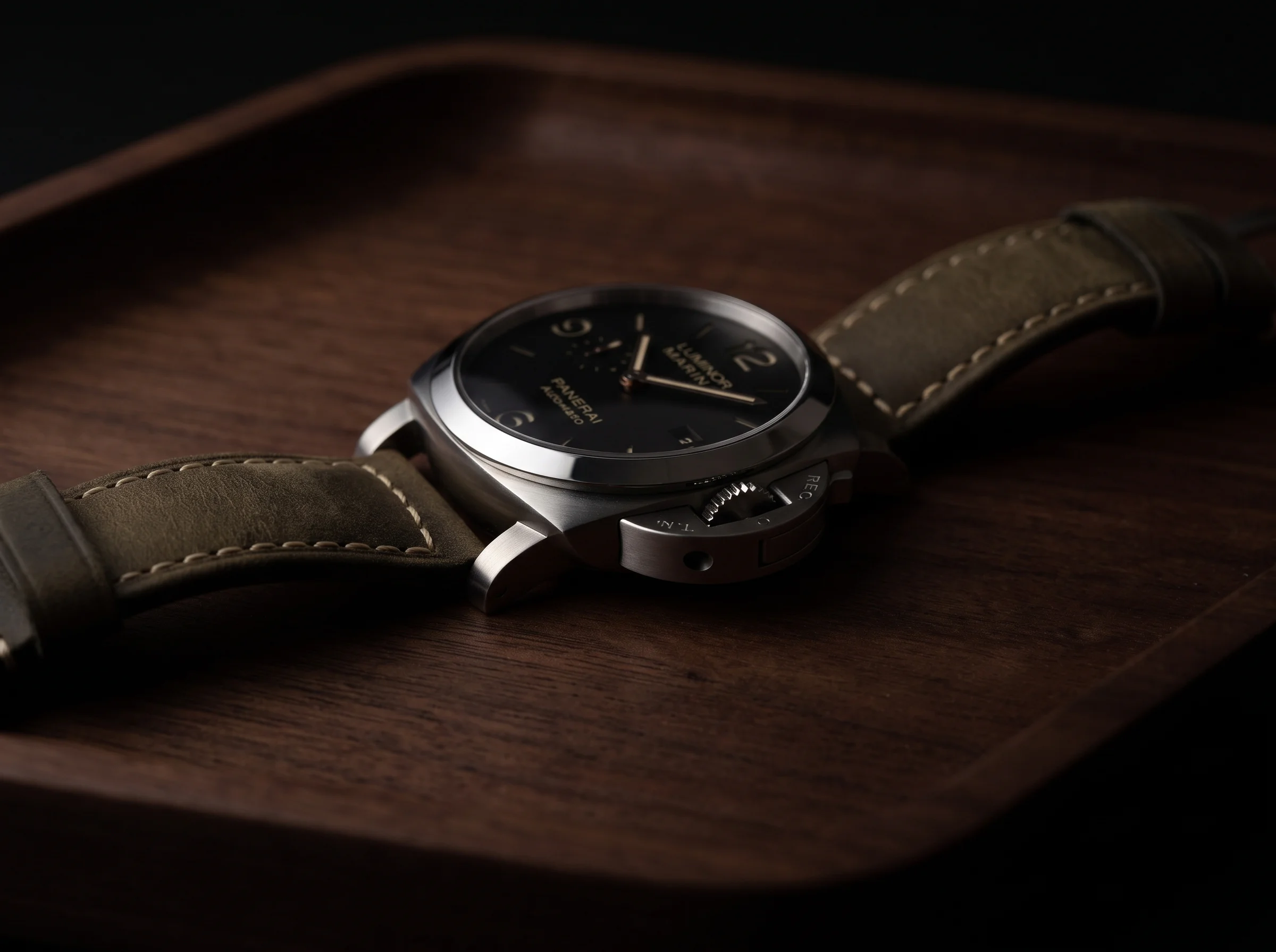 Detail of the lever-locking crown-guard bridge on a cushion-case watch on a walnut desk
