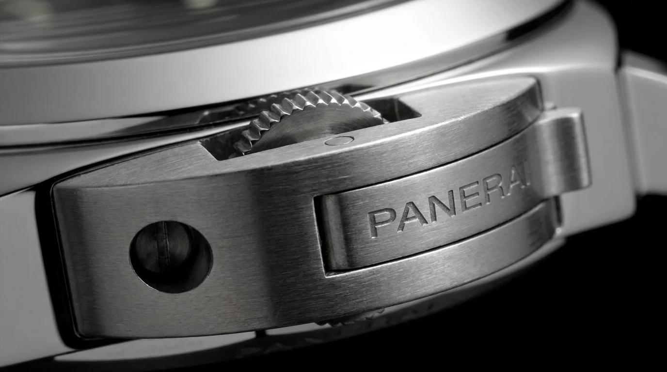Macro closeup of a Panerai dive watch's crown-guard lever lock mechanism with PANERAI engraved on the bridge.