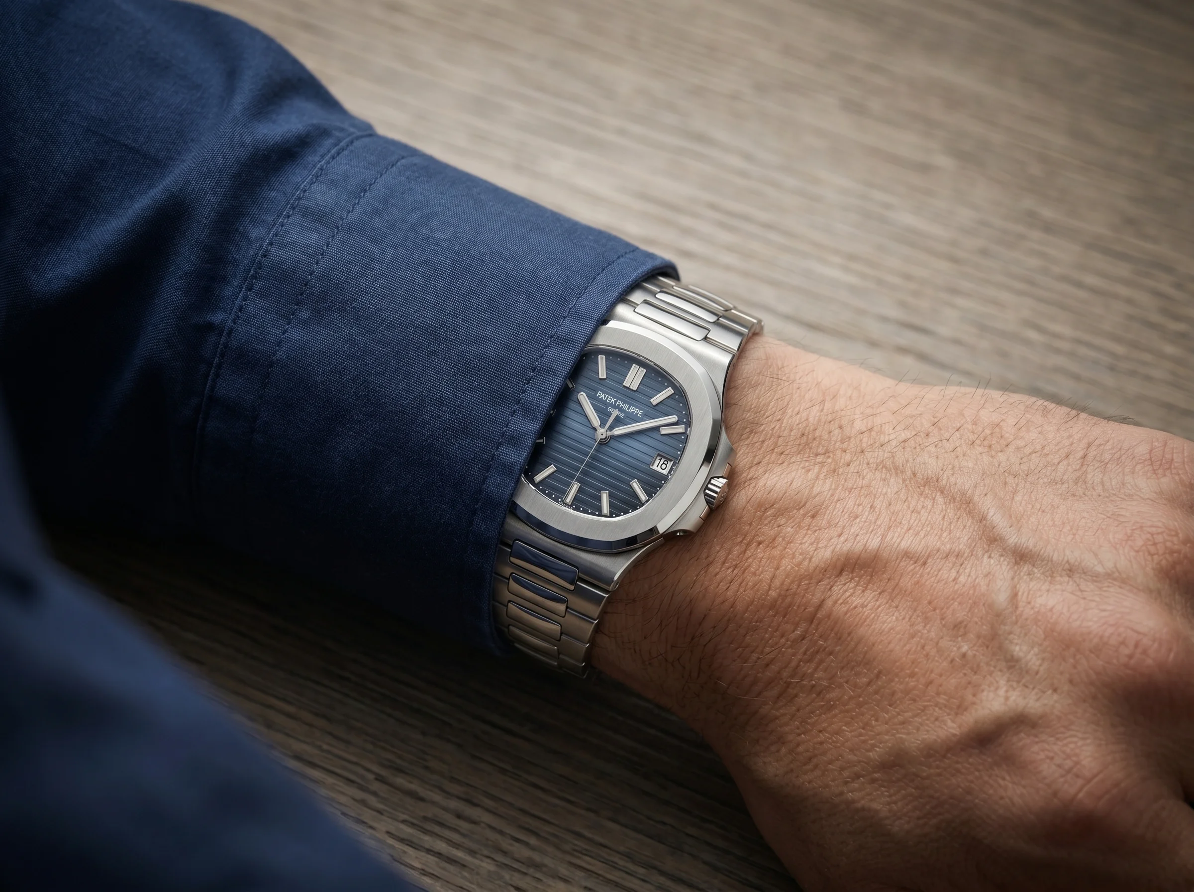 Patek Philippe Nautilus with blue dial worn on a wrist slipping under a tailored shirt cuff