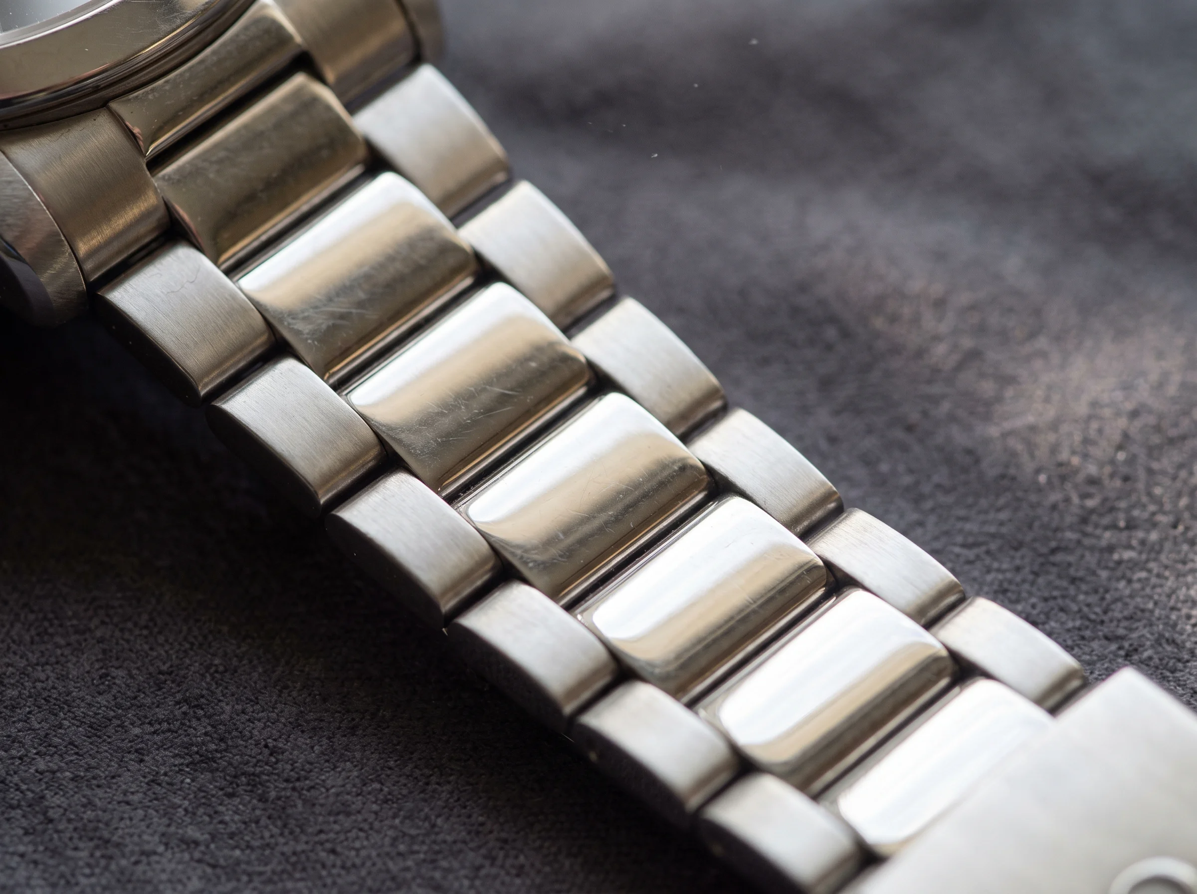 Extreme close-up of a stainless steel multi-link bracelet showing polished center links and brushed outer links