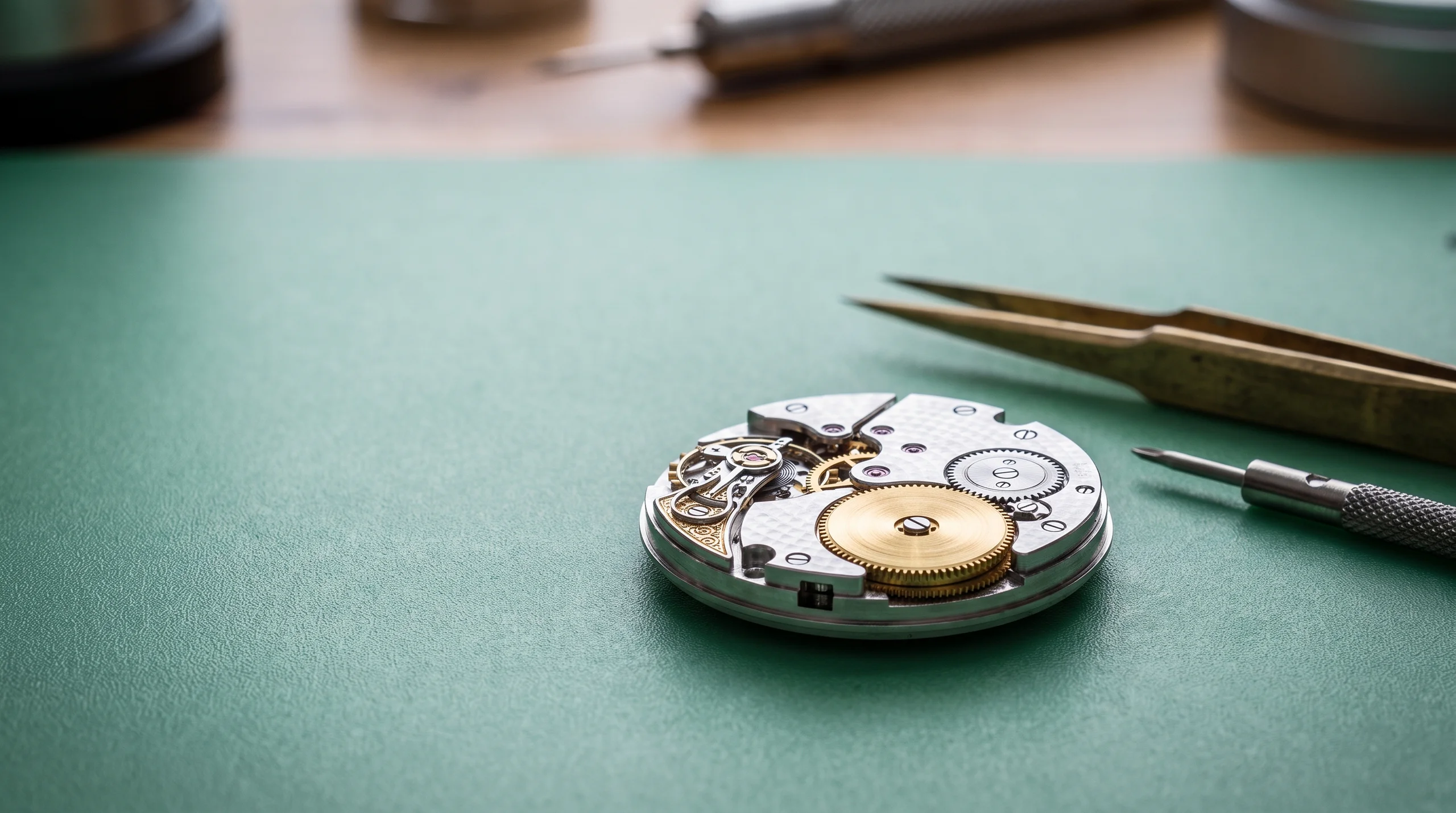 Watch movement on a watchmaker bench showing the barrel and gears