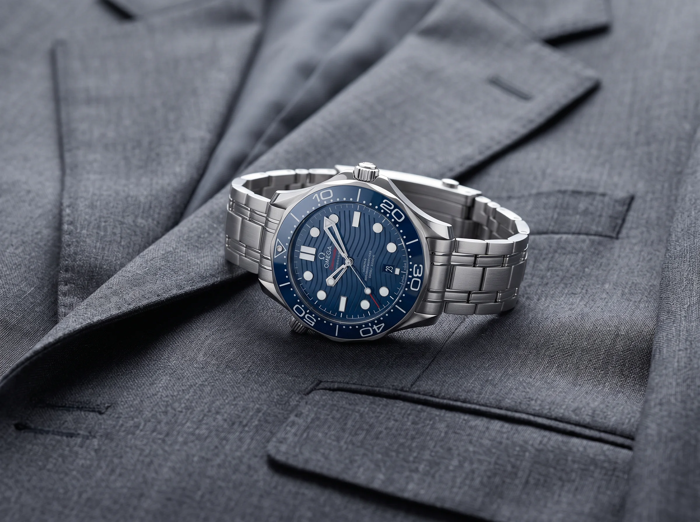 Stainless steel blue dial dive watch on a folded charcoal suit jacket