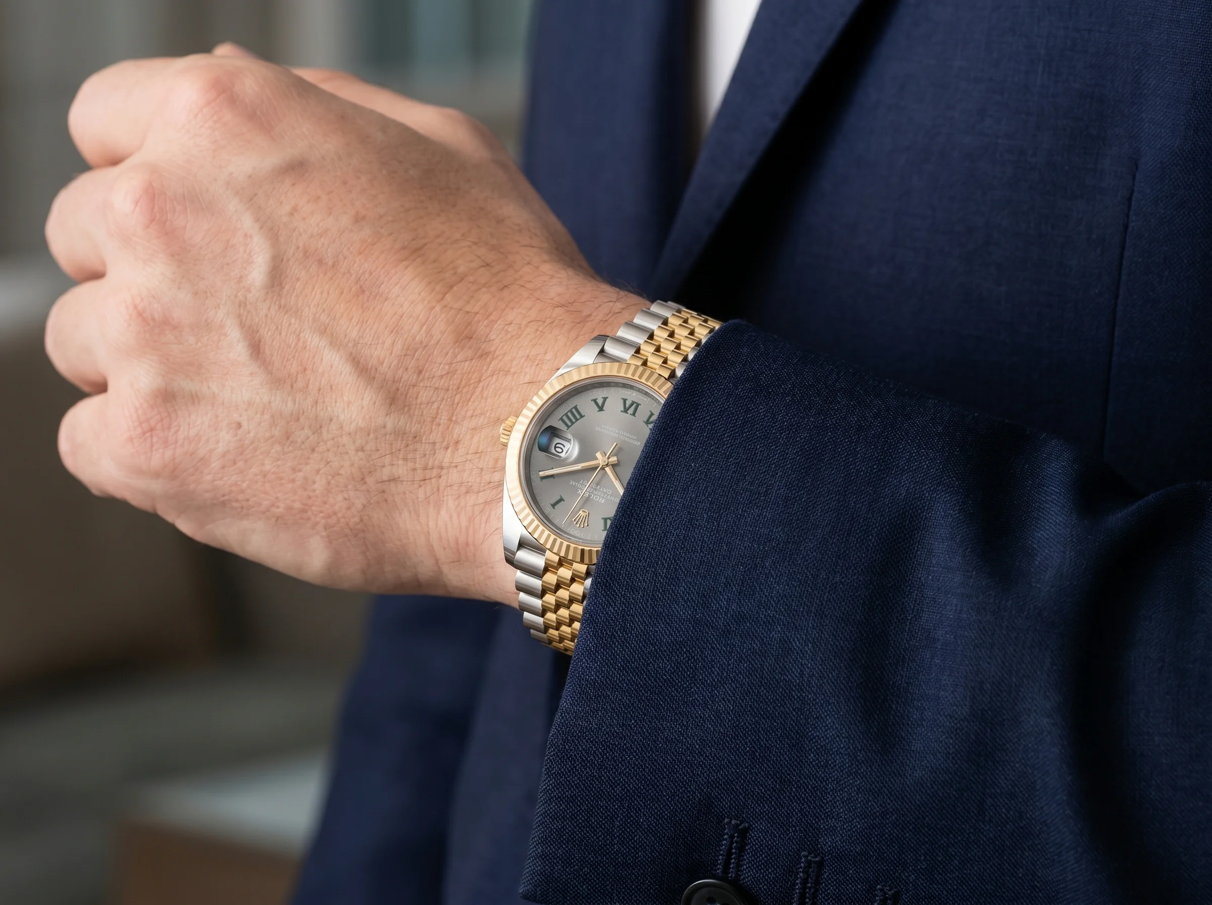 Two-tone steel and gold watch worn on a wrist under a tailored suit cuff