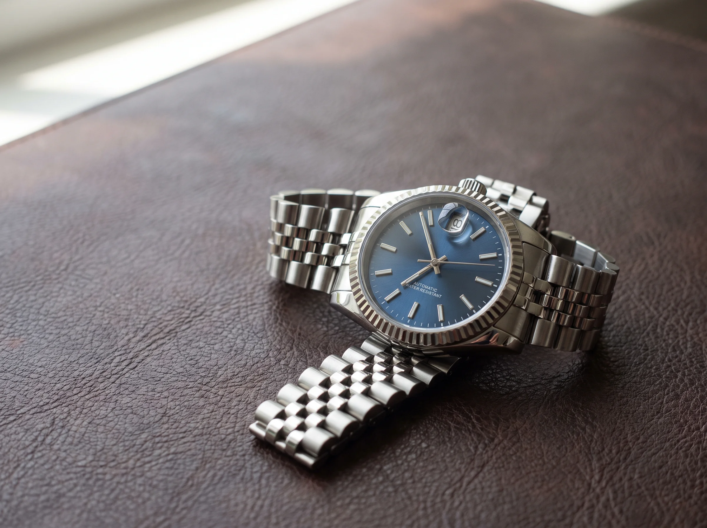 Rolex Datejust with a fluted bezel, blue dial, cyclops date at 3 o'clock, and a five-link Jubilee bracelet