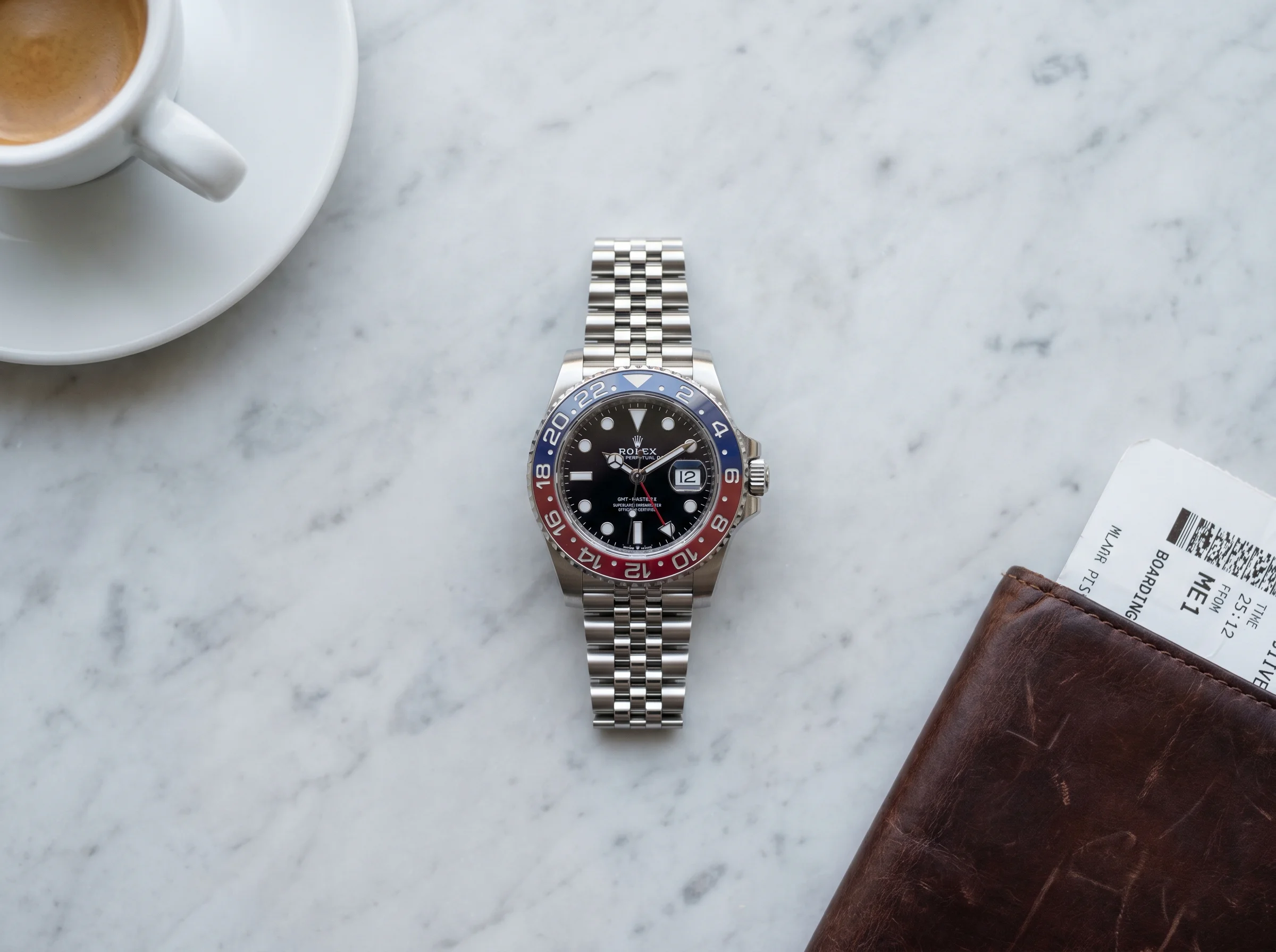 Top-down view of the Rolex GMT-Master II Pepsi 126710BLRO on a marble bistro table with a leather passport and folded boarding pass, showing the discontinued red and blue Cerachrom bezel that drove the post-Watches and Wonders 2026 price surge.