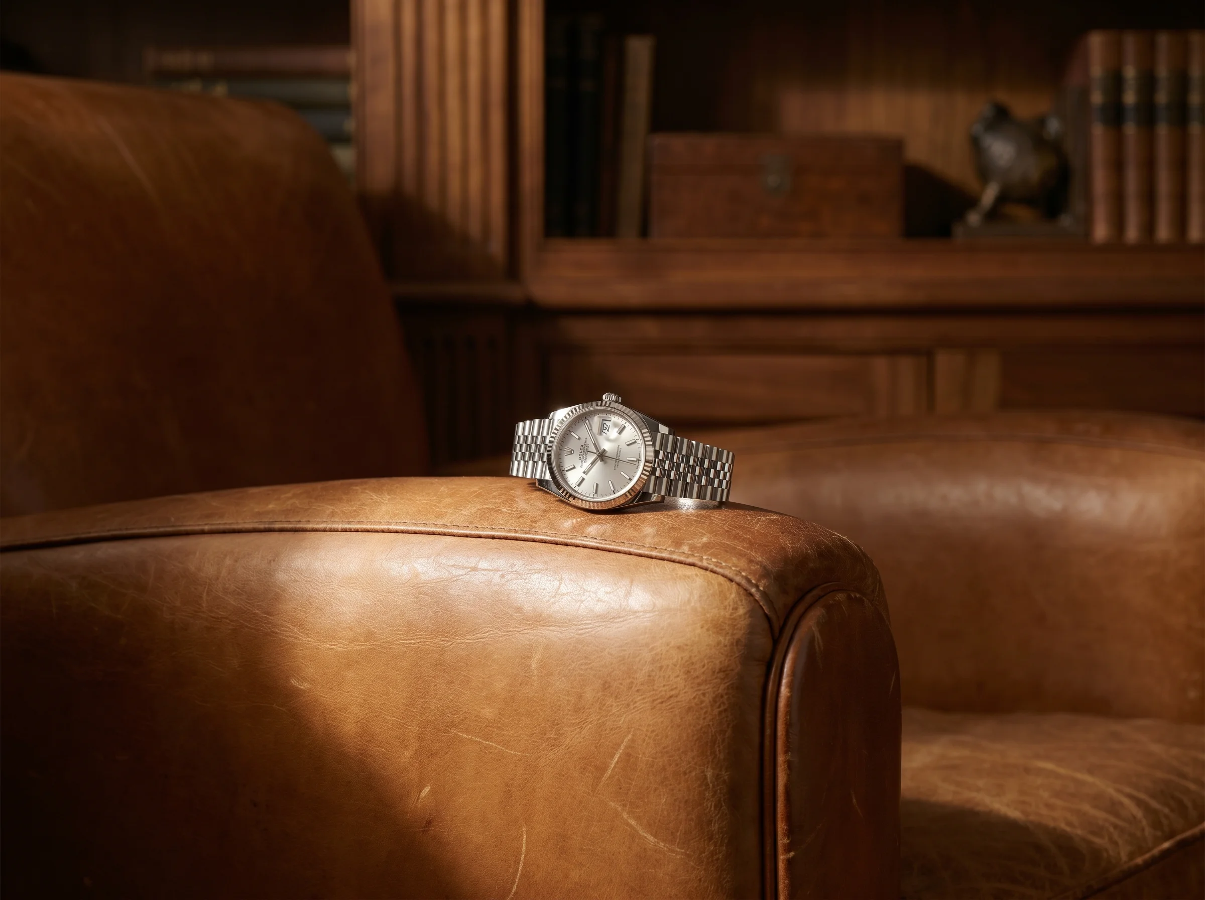 Rolex Datejust 36 on a five-link Jubilee bracelet resting on the arm of a tan leather club chair