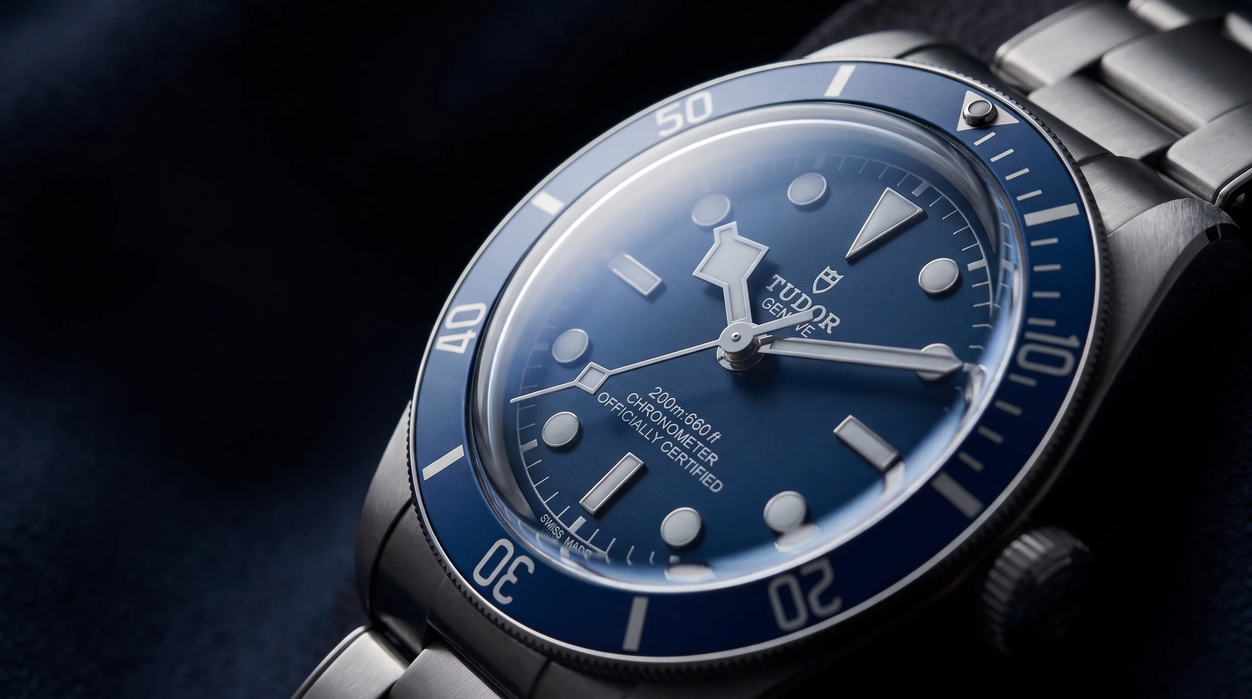 Macro of a domed sapphire crystal with blue anti-reflective coating on a dive watch, the hardest common watch crystal