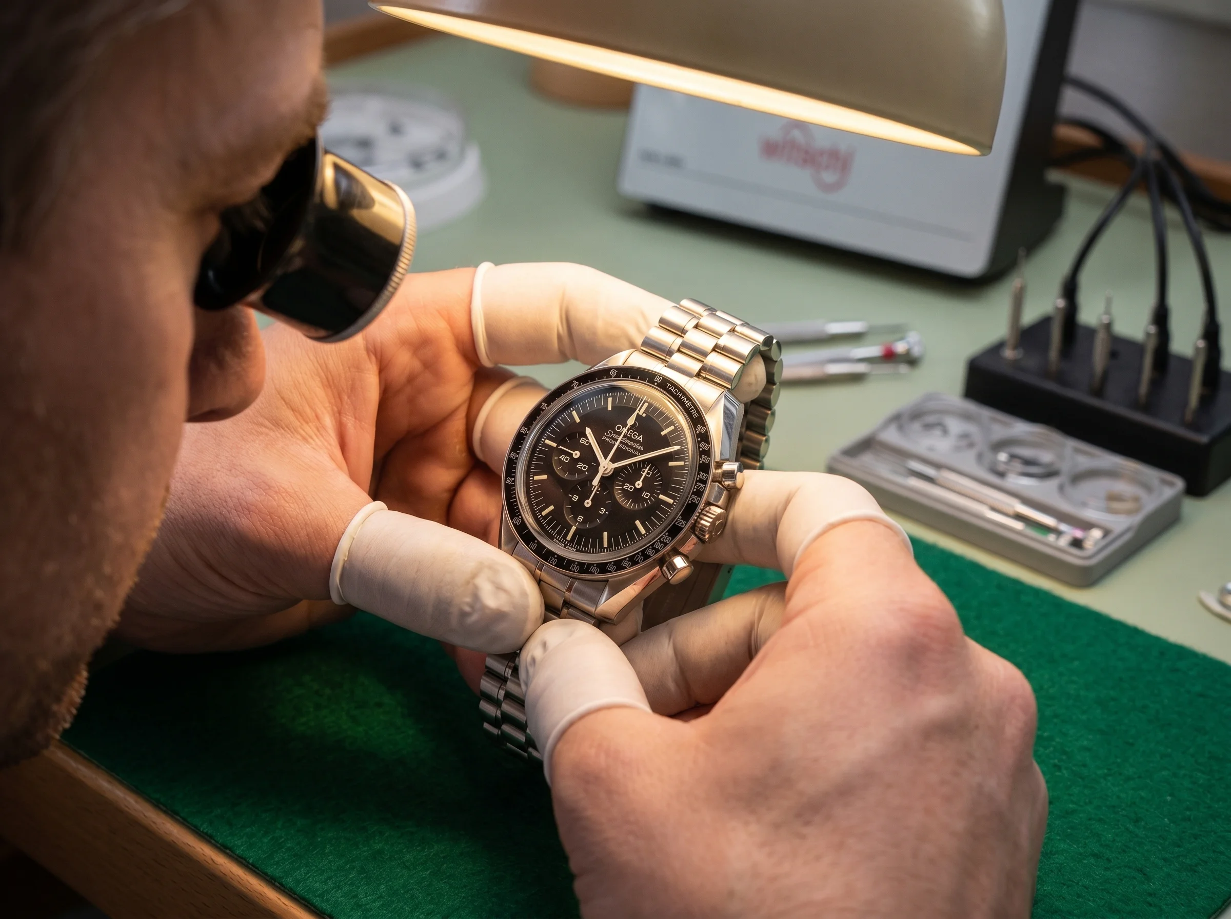Watchmaker doing a final inspection on a reassembled Omega Speedmaster Moonwatch after service