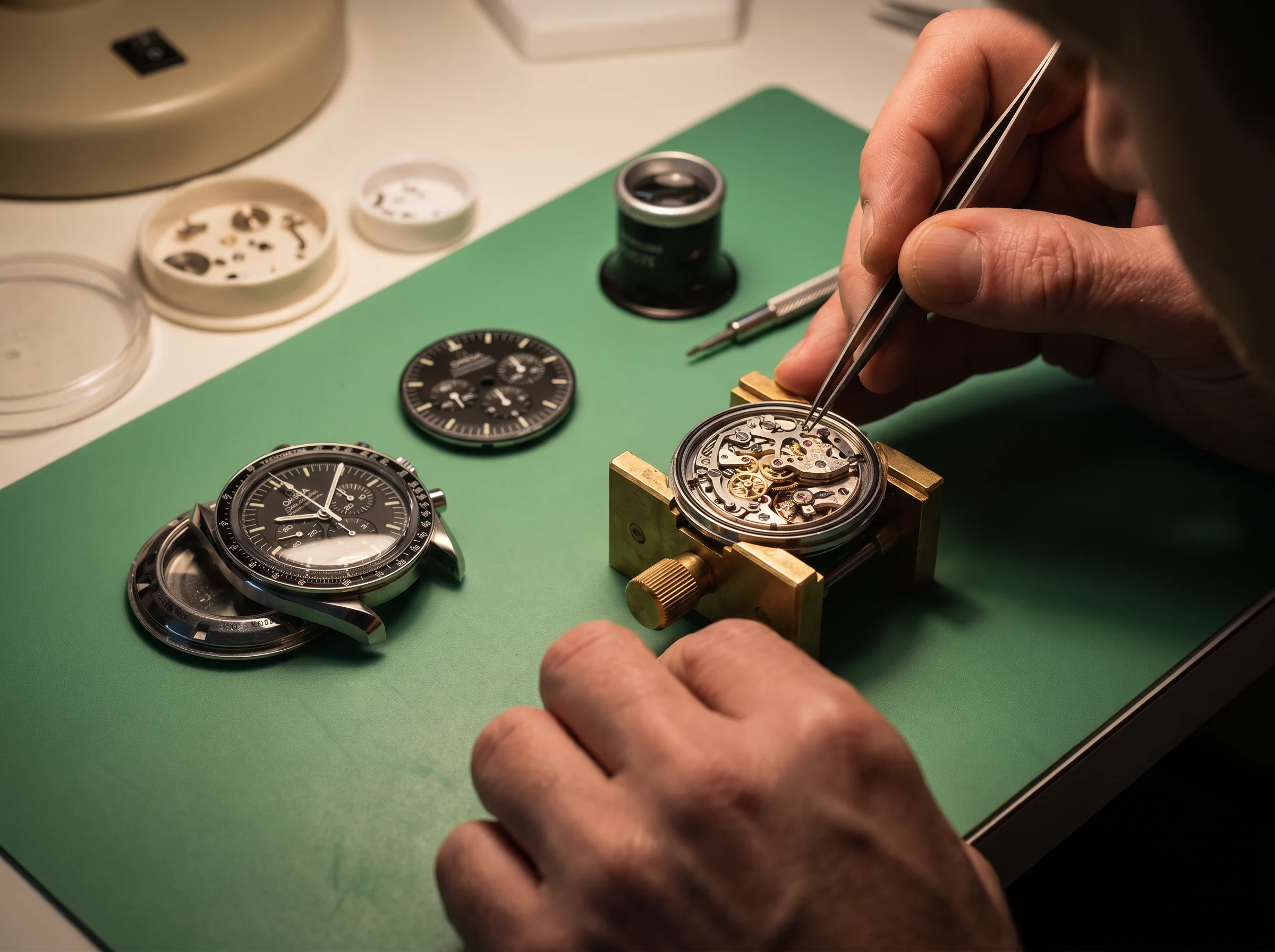 Watchmaker working on an Omega Speedmaster Moonwatch with the caseback removed and the movement exposed