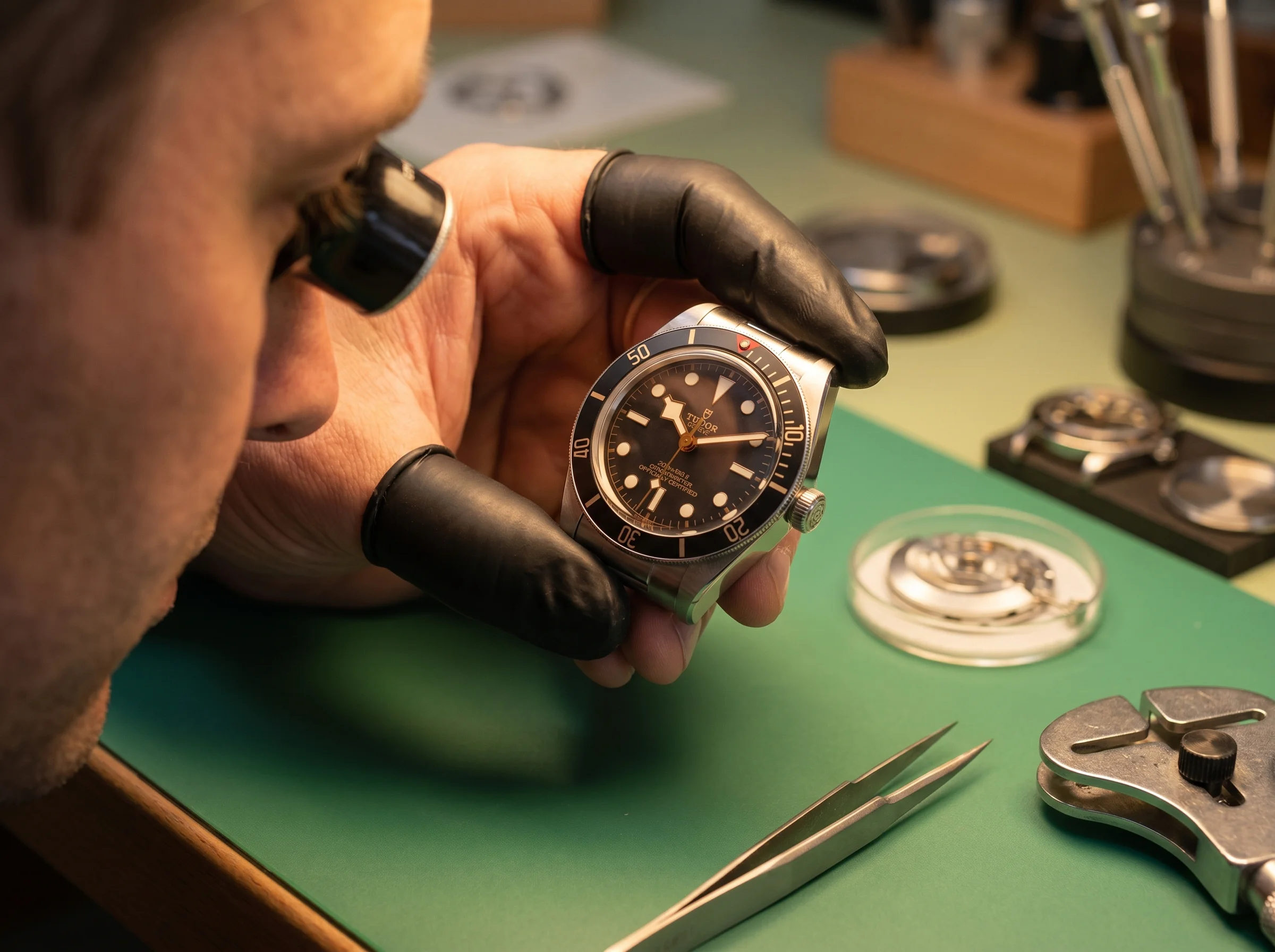 Watchmaker inspecting a Tudor Black Bay Fifty-Eight under a loupe during a service