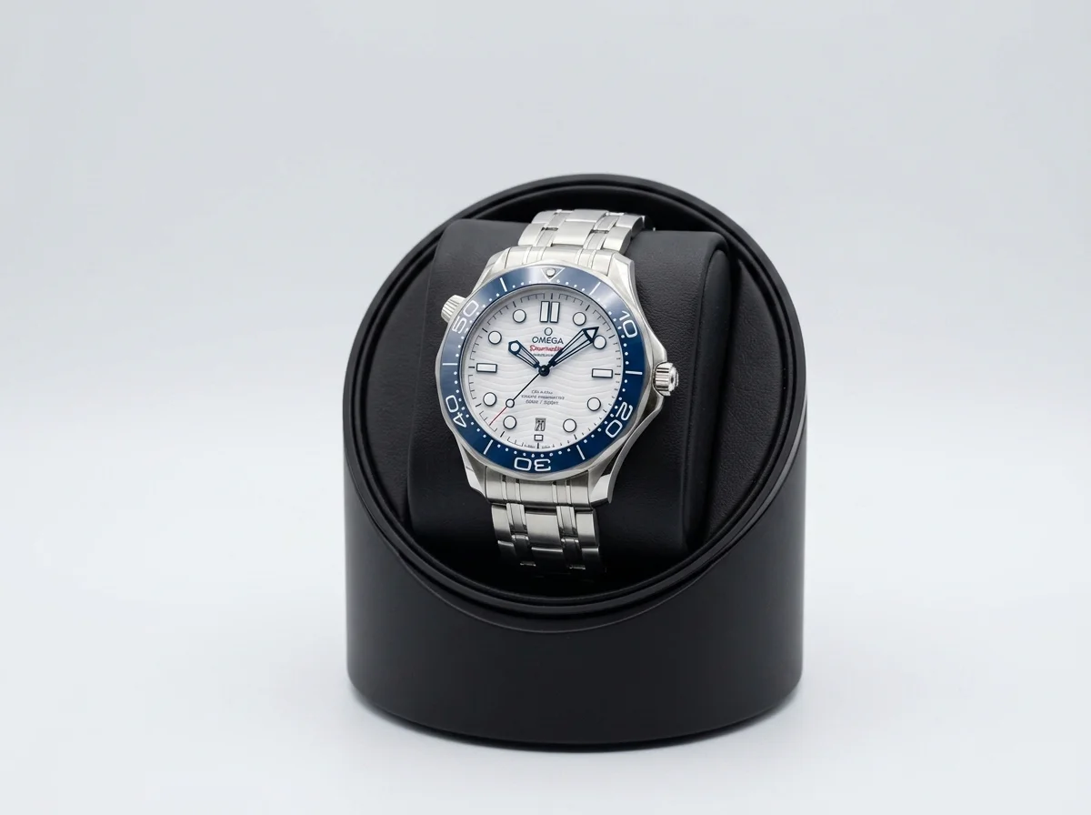 An Omega Seamaster Diver 300M with a white wave dial seated on a single matte-black watch winder